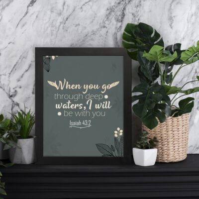 Infidu Isaiah 43:2 Bible Wall Art with dark gray background, beige text in elegant script and bold fonts, and delicate leaf patterns. displayed on the table in a black frame