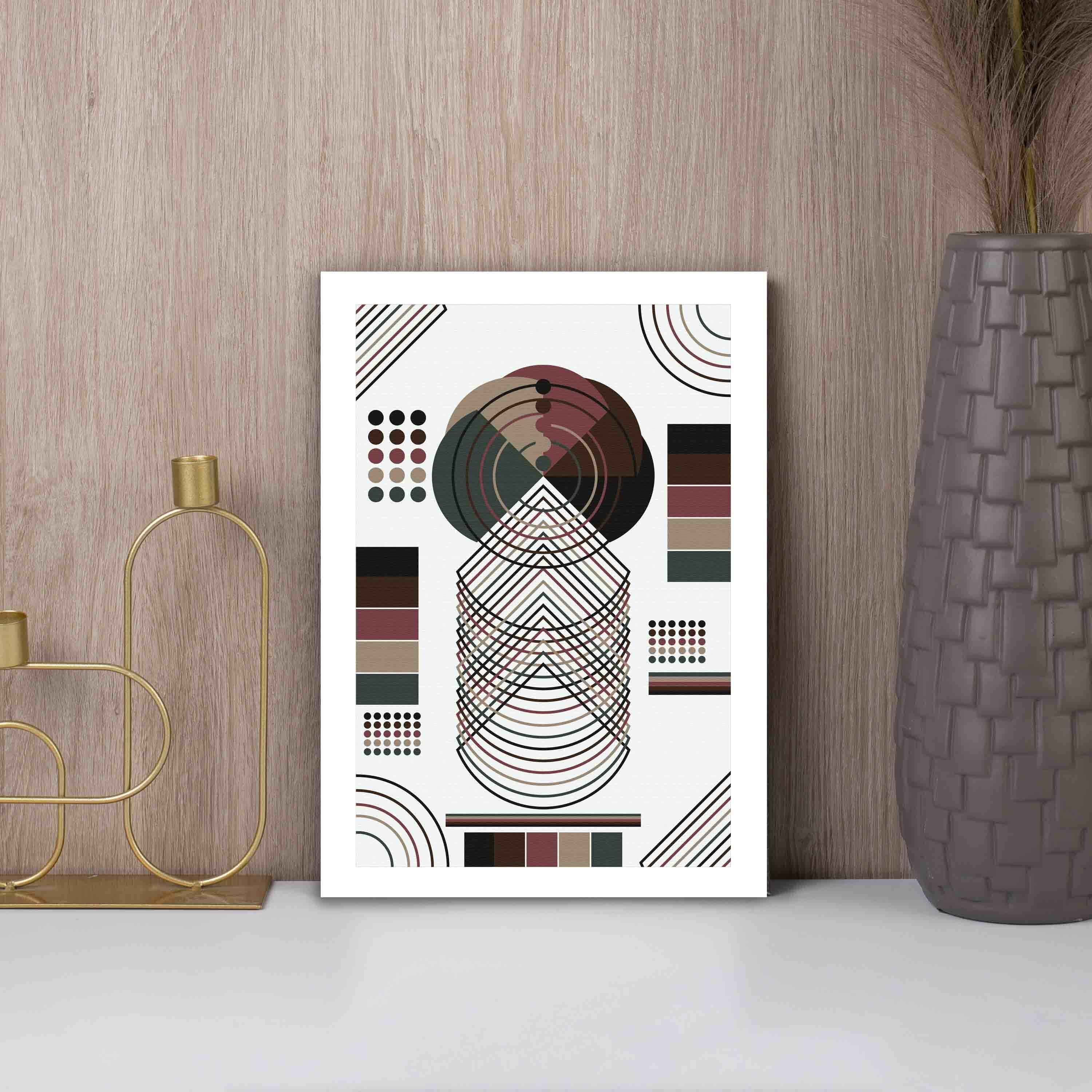 Abstract wall art with geometric shapes in brown, black, beige, and dark green, framed in white, displayed on a white background.