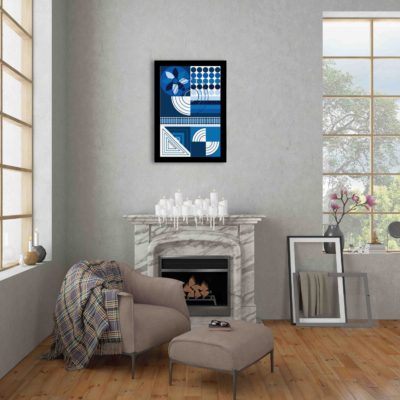Abstract wall art with geometric shapes in blue, white, and black, framed in black, displayed on a light gray wall in a cozy setting.