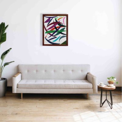 Abstract wall art with overlapping red, green, blue, purple, and pink shapes on a textured white background, framed in brown wood.