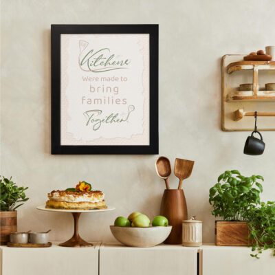 Kitchens were made to bring families together in soft cursive font on a light beige background, creating a cozy and modern kitchen atmosphere. There is a vegetable table, and above it, there is wall art.