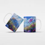 White coffee mug with a colorful floral design, featuring bright flowers, green grass, a blue sky with clouds, and mountains in the background.