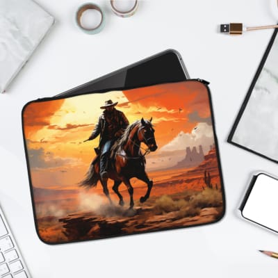 Laptop sleeve featuring a cowboy on a horse with a vibrant sunset background in orange and yellow tones, desert terrain, and rock formations. laptop sleeve kept on a plain white background