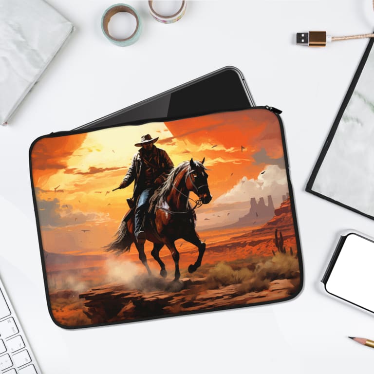 Laptop sleeve featuring a cowboy on a horse with a vibrant sunset background in orange and yellow tones, desert terrain, and rock formations. laptop sleeve kept on a plain white background