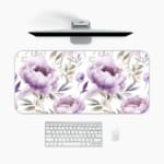 Infidu Soft Floral Desk Pad with white background, large purple and lavender flowers, and light gray and blue leaves. A desk pad under the computer