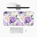 Infidu desk pad with colorful floral design on white background. Features large yellow and purple flowers with green and grayish leaves. A desk pad under the computer