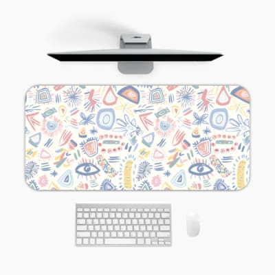 Desk pad with whimsical symbols including eyes, geometric shapes, and abstract designs in light blue, pink, and orange. A desk pad under the computer