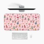 Infidu desk pad with playful floral and figures design on a light pink background, featuring colorful flowers and figures. A desk pad under the computer