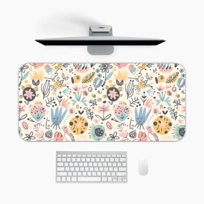 Infidu desk pad with soft pastel floral design on a light pink background, featuring delicate light blue, pink, and beige flowers. A desk pad under the computer