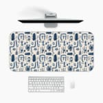 Blue abstract patterns including geometric shapes and faces on a white desk pad. A desk pad under the computer