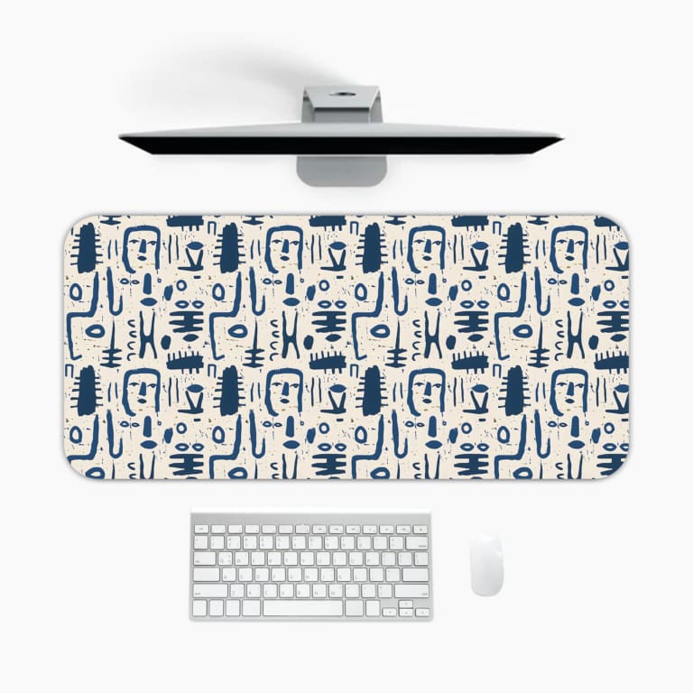 Blue abstract patterns including geometric shapes and faces on a white desk pad. A desk pad under the computer