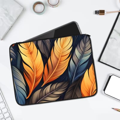 Laptop sleeve with an elegant feather design in gold, blue, and gray on a dark background, made with durable fabric and secure zipper closure. laptop sleeve kept on a plain white background