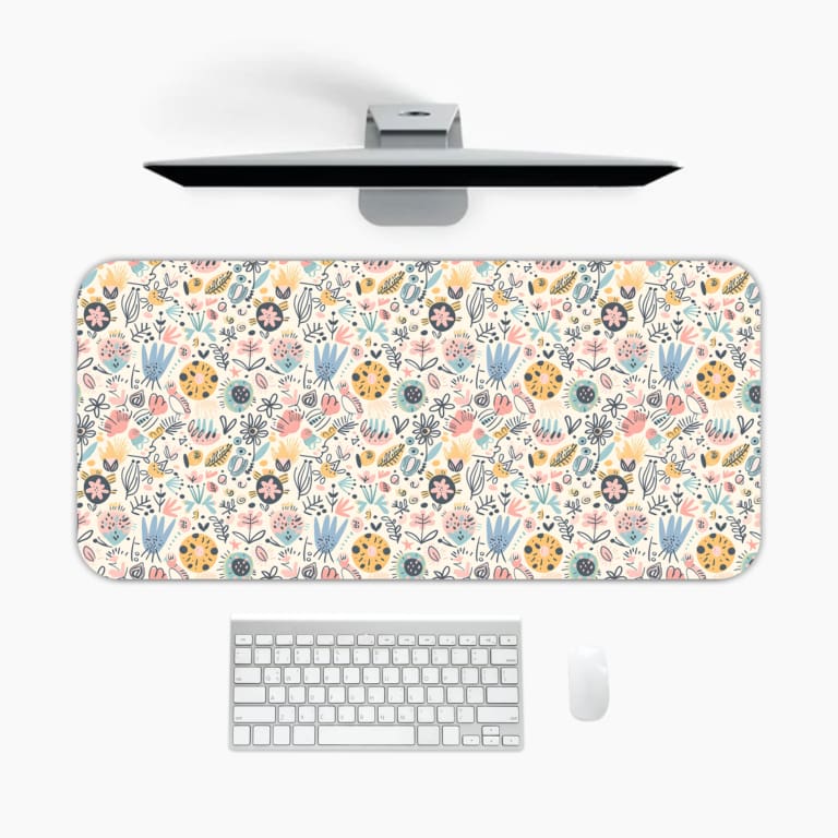 Desk pad with soft pastel floral design in pink, blue, and beige on a light cream background. A desk pad under the computer
