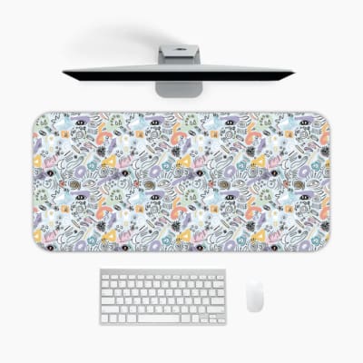 Desk pad with colorful abstract shapes in orange, black, white, and blue on a light blue background. A desk pad under the computer