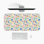 Desk pad with playful, colorful drawings of animals and plants on a white background. A desk pad under the computer