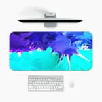 Infidu Abstract Desk Pad with blue, purple, and green colors, featuring sharp and flowing lines on a light background. A desk pad under the computer