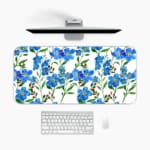 Blue floral desk pad with green leaves on a white background. A desk pad under the computer