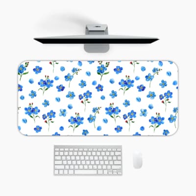Desk pad with small blue flowers and dark green leaves on a white background. A desk pad under the computer