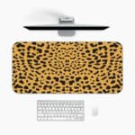 Infidu Leopard Print Desk Pad features a leopard print pattern with a tan background and black spots, resembling natural leopard fur. A desk pad under the computer