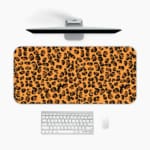 Infidu Leopard Print Design Desk Pad with black spots on a yellow background, simulating a leopard's natural fur. A desk pad under the computer