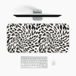 Infidu Bold Black and White Abstract Print Desk Pad with black abstract shapes on a white background, resembling animal print. A desk pad under the computer
