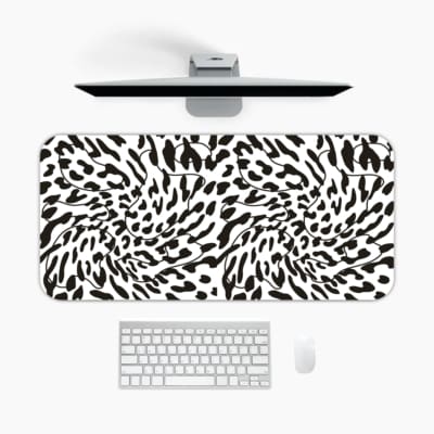 Infidu Bold Black and White Abstract Print Desk Pad with black abstract shapes on a white background, resembling animal print. A desk pad under the computer