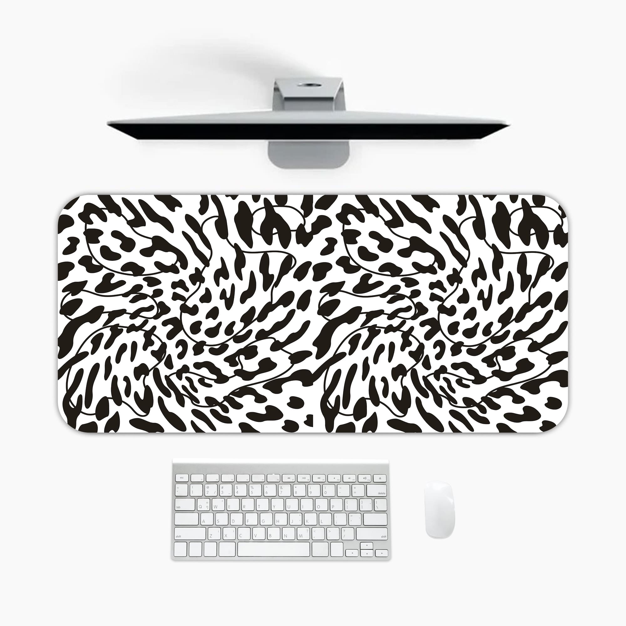 Infidu Bold Black and White Abstract Print Desk Pad with black abstract shapes on a white background, resembling animal print. A desk pad under the computer