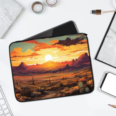 Laptop sleeve featuring a serene sunset desert landscape with mountains, cacti, and a dramatic sky, made with durable fabric and a secure zip. laptop sleeve kept on a plain white background