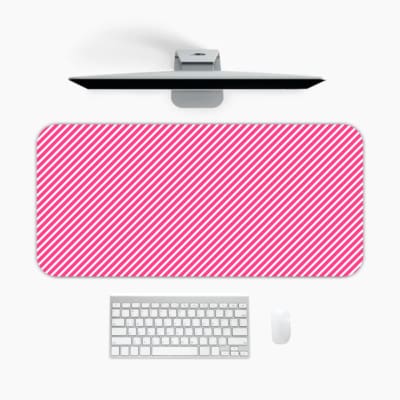 Pink diagonal striped desk pad with a soft and pastel design, featuring thin pink stripes on a light background. A desk pad under the computer