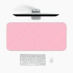 Light pink diagonal striped desk pad with a soft and pastel design, featuring thin pink stripes on a light background. A desk pad under the computer
