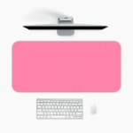 Bright pink desk pad with subtle dotted design, adding a textured look to a simple background. A desk pad under the computer