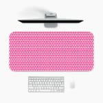Pink desk pad with a pattern of small, evenly spaced triangles. A desk pad under the computer