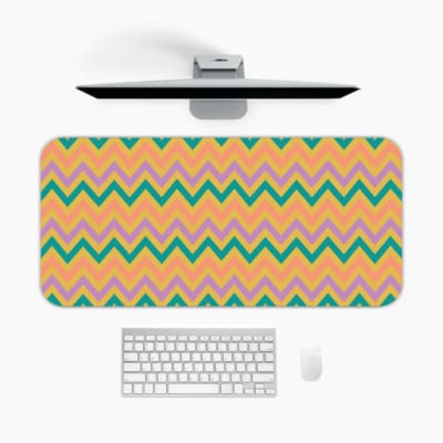 Infidu Teal and Purple Chevron Desk Pad with Peach Background featuring a zigzag pattern in vibrant teal and purple tones. A desk pad under the computer