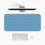Desk pad featuring small black polka dots on a blue background. A desk pad under the computer