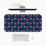 Infidu Red Strawberry and Blue Leaf Desk Mat with a dark blue background and a vibrant pattern of red strawberries and blue leaves. A desk pad under the computer