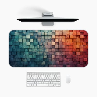 Desk mat with a gradient cube design, transitioning from cool blue and teal tones to warm orange hues on a white background. A desk pad under the computer