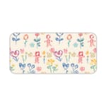 Desk pad with childlike drawings of flowers, stick figures, and hearts in pastel blue, pink, and yellow. Desk Pad kept on a plain white background