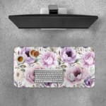 Infidu Flowers Design Desk Pad with green leaves and large purple and pink flowers on a light, neutral background. Desk Pad with Keyboard and Mouse on top of the desk pad