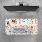 Desk pad with childlike drawings of flowers, stick figures, and hearts in pastel blue, pink, and yellow. Desk Pad with Keyboard and Mouse on top of the desk pad