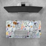 Infidu desk pad with pastel abstract shapes and symbols on a pale blue background. Desk Pad with Keyboard and Mouse on top of the desk pad