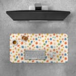 Colorful star-like flowers on a light pink background desk pad by Infidu, featuring vibrant red, blue, orange, green, and pink floral patterns. Desk Pad with Keyboard and Mouse on top of the desk pad