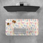 Desk pad with a light background featuring a colorful pattern of floral and abstract shapes in blue, pink, yellow, and green. Desk Pad with Keyboard and Mouse on top of the desk pad