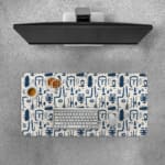 Blue abstract patterns including geometric shapes and faces on a white desk pad. Desk Pad with Keyboard and Mouse on top of the desk pad