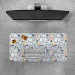 Desk pad with colorful abstract shapes in orange, black, white, and blue on a light blue background. Desk Pad with Keyboard and Mouse on top of the desk pad