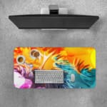 Desk pad with a vibrant abstract swirl design in orange, yellow, gray, blue, and pink. Desk Pad with Keyboard and Mouse on top of the desk pad
