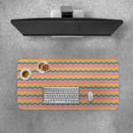 Desk pad with wavy lines in purple, green, and yellow on a light pink background. Desk Pad with Keyboard and Mouse on top of the desk pad