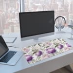 Infidu desk pad with purple and white flowers and green leaves on a white background. A computer and laptop are next to the desk pad
