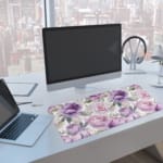Infidu Floral Desk Pad featuring purple and light pink flowers with green and grayish leaves on a light white background. A computer and laptop are next to the desk pad