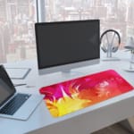 Desk pad with a vibrant pink and yellow abstract design. A writing pad on top of the desk pad