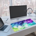 Infidu Watercolor Gradient Abstract Desk Pad with vibrant blue, purple, green, and white colors in a gradient pattern. A computer and laptop are next to the desk pad